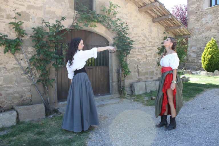 Dos intèrprets fent una escena d’esgrima teatral amb espases